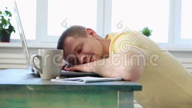 自由职业程序员在带笔记本电脑的办公桌上因疲劳而睡着